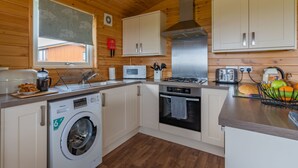Cocina compacta con paredes de madera, lavadora, microondas, estufa y tostadora.