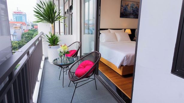 A balcony with a bed, two chairs, a table, and a potted plant. - CELINA HOTLE Ninh Bình (Hoa Lu)