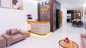 A hotel reception area with a modern design, including a reception desk, seating area, and a dining space. - CELINA HOTLE Ninh Bình (Hoa Lu)