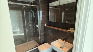 A modern bathroom with a glass-enclosed shower, a white toilet, and a sink with a mirror above. - Apt Sleeps 6 With Two Bathrooms (Manchester)