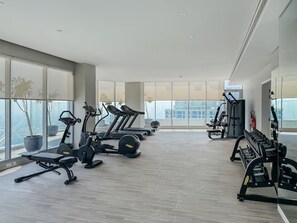 A modern gym with treadmills, elliptical machines, and weight stations.