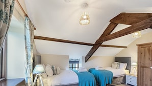 A bedroom with two beds, a wooden ceiling, a radiator, a lamp, and a window with curtains. - The Cider Barn, Waterrow, Nr Wivelsicombe (Waterrow)