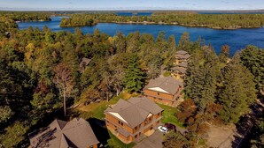 A residential area with multiple houses surrounded by dense forests and a large body of water.