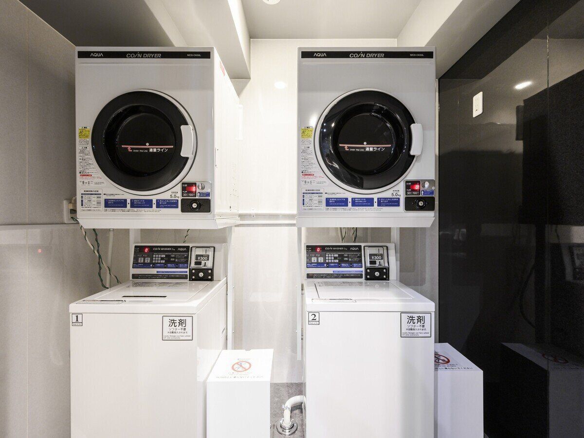 A laundry facility with two front-loading machines and two top-loading machines, each with a control panel and a label indicating the machine number.