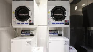 A laundry facility with two front-loading machines and two top-loading machines, each with a control panel and a label indicating the machine number.