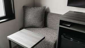 A corner of a room with a grey sofa, a small table, and a built-in appliance. - HOTEL NOIR Kagoshima Chuo Station (Kagoshima)