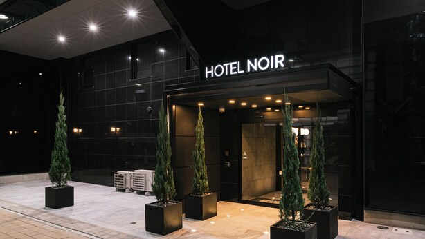 The exterior of HOTEL NOIR with a modern facade, large glass windows, and a prominent entrance. - HOTEL NOIR Kagoshima Chuo Station (Kagoshima)