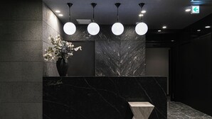 A reception area with a marble counter, a vase of flowers, and pendant lighting. - HOTEL NOIR Kagoshima Chuo Station (Kagoshima)