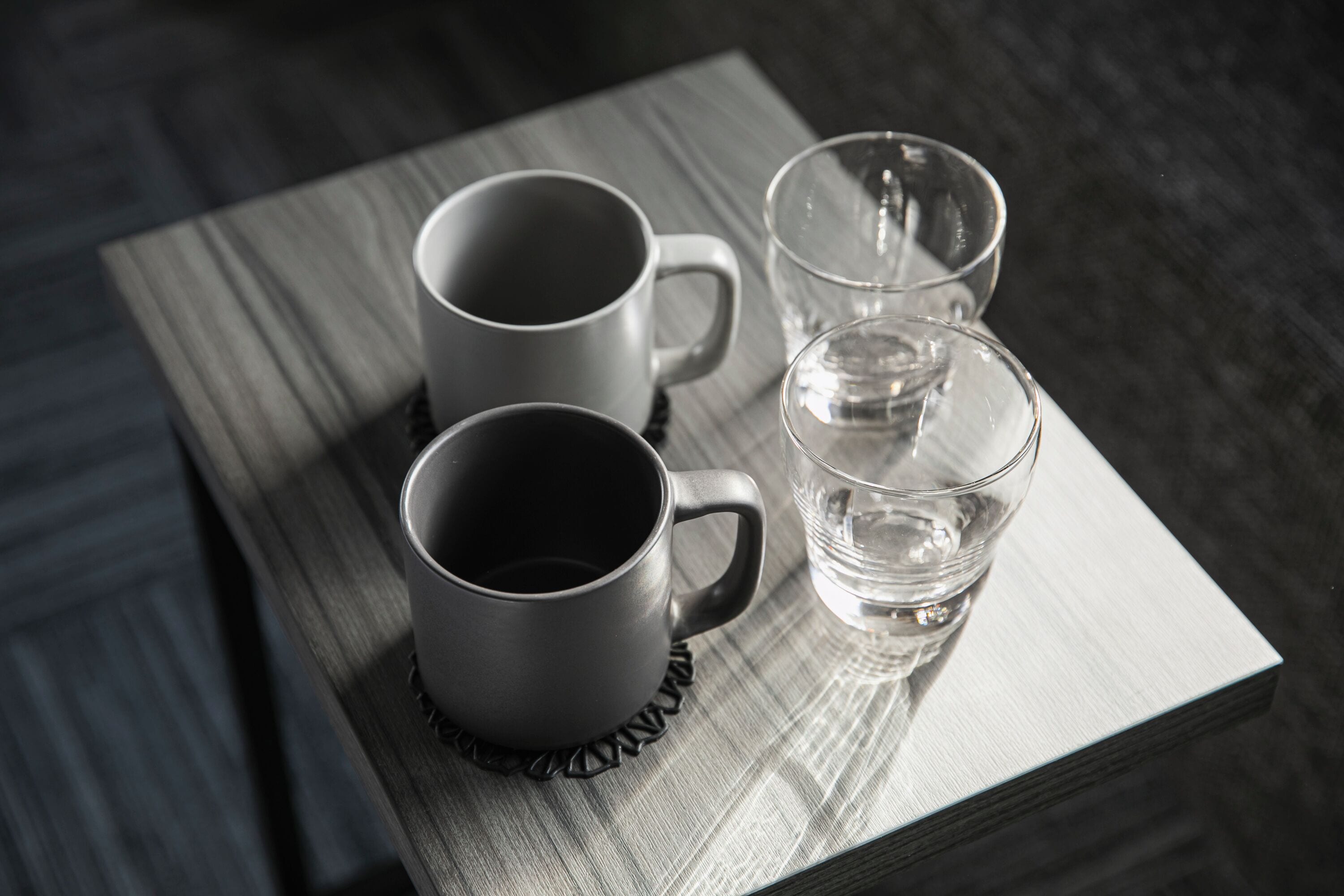 Three mugs and a glass on a wooden tray.
