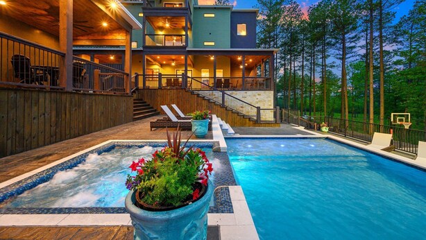 A multi-level house with a swimming pool, outdoor seating, and a basketball court. - Luxury Cabin | Heated Pool, Hot Tub, Game Loft, Pickleball Court | Sleeps 23 – Risky Business (Broken Bow)