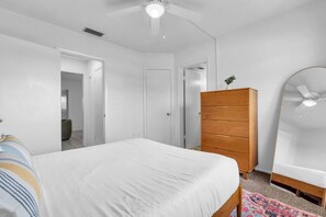 A bedroom with a bed, a wooden dresser, a mirror, and a ceiling fan. - Lido Key, Steps to Lido Beach, Walk to St. Armands Circle, 2 Suites (Sarasota)