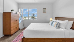 A bedroom with a bed, a dresser, a window with a view, and a ceiling fan. - Walk to Lido Beach Tiki Bar, 2 Queen Suites (Sarasota)