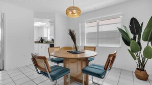A dining area with a round table, chairs, and a hanging light fixture. - Walk to Lido Beach Tiki Bar, 2 Queen Suites (Sarasota)