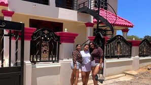 A two-story building with a red and white facade, a gated entrance, and a staircase leading to the upper floor. - Homes for rent vacation rentals vacation rentals los Conuco de Villavaquez (Monte Plata)