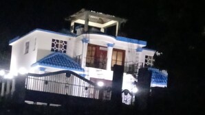 A building with a white facade and blue accents, featuring a balcony and a small tower-like structure on top. - Homes for rent vacation rentals vacation rentals los Conuco de Villavaquez (Monte Plata)