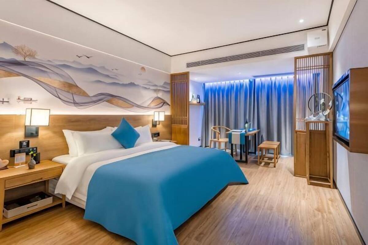 Une chambre d’hôtel avec un grand lit, des tables de chevet, un bureau et une télévision.