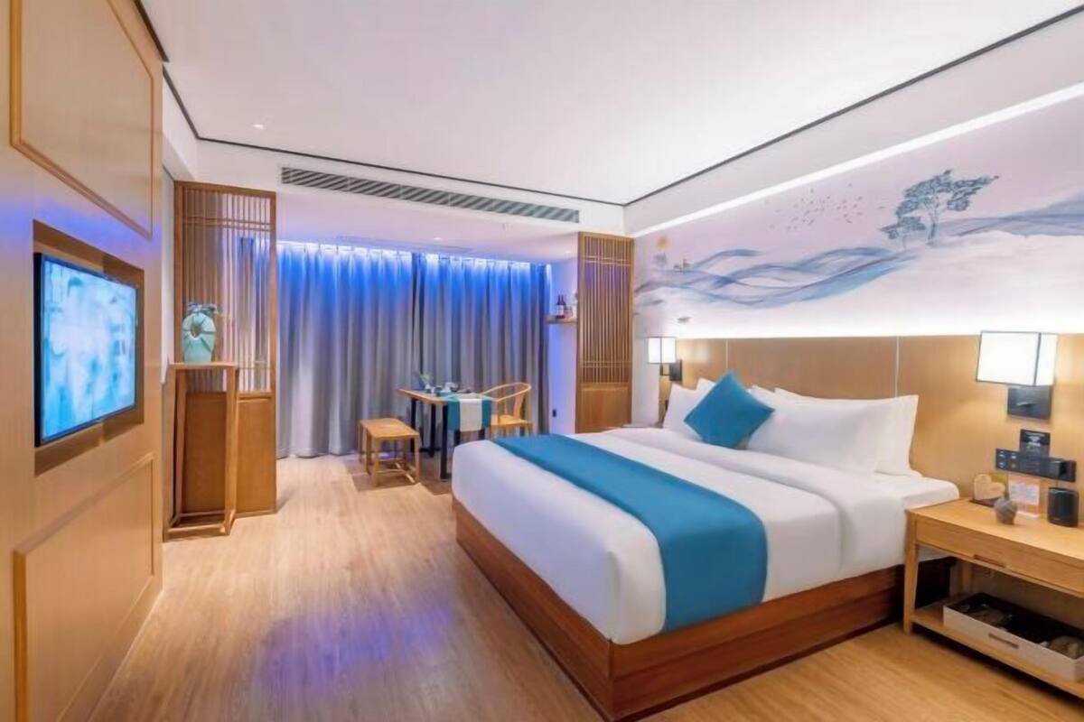 Une chambre d’hôtel équipée d’un lit, d’une table de chevet, d’une télévision et offrant une vue sur l’extérieur.