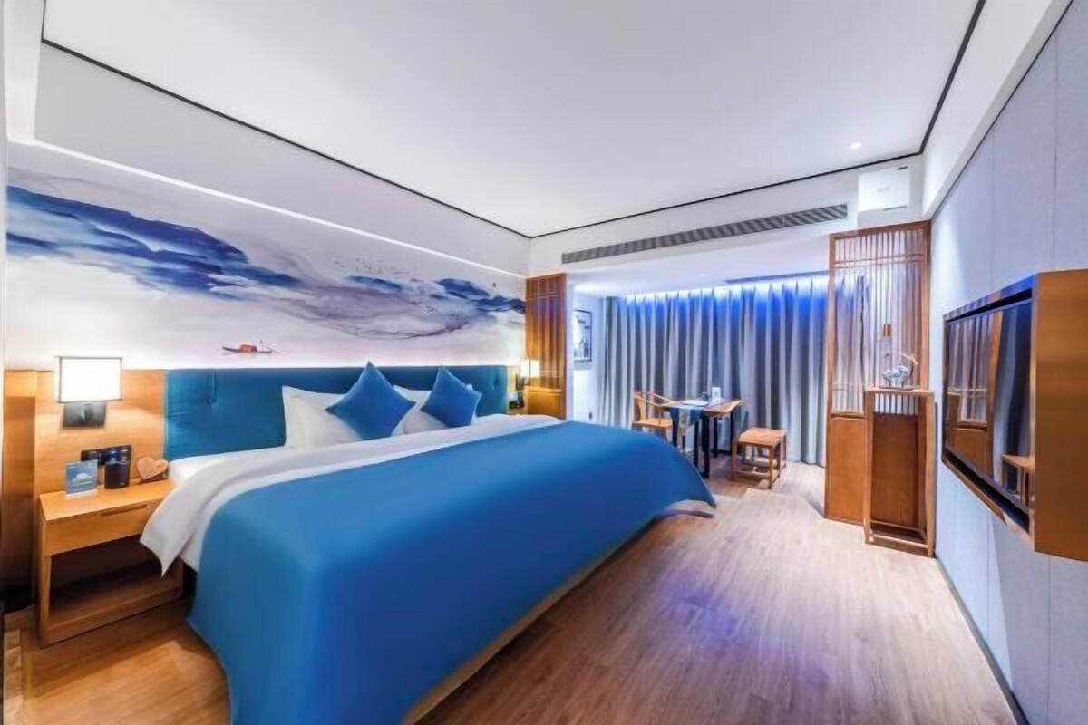 Une chambre d’hôtel moderne avec un grand lit, un bureau et une vue sur le ciel.