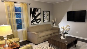 Una sala de estar con un sofá, una mesa de centro y un televisor montado en la pared.