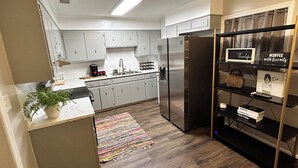 Una cocina moderna con armarios grises, un refrigerador de acero inoxidable y un estante con temática de café.