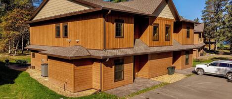 Une maison en bois à deux étages, avec un garage, une véranda et une allée.