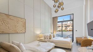 Een moderne hotelkamer met een groot bed, een bank, een eethoek en een balkon met uitzicht op gebouwen.