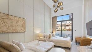 A modern hotel room with a large bed, a sofa, a dining area, and a balcony with a view of buildings.