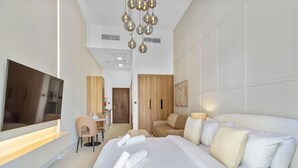 Een hotelkamer met een groot bed, een bureau, een stoel, een televisie en een moderne kroonluchter.