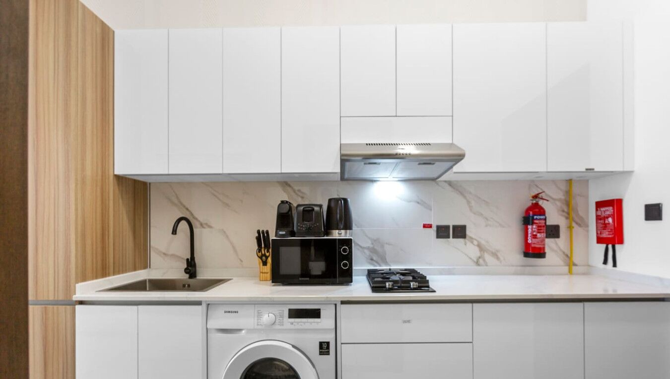 A compact kitchen with a built-in washing machine, a microwave, and a gas stove.