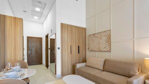 Een moderne hotelkamer met een eethoek, een bank en een grote spiegel.