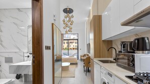 A modern kitchen with a built-in oven, a coffee machine, and a sink. - Luxe Interior Studio in Pantheon Elysee 3 in JVC (Dubai)