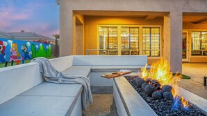 A patio with a fire feature, a colorful mural, and a building with large windows. - ALL INCLUSIVE - SUPER MARIO RETREAT – EPIC GAMING GETAWAY (Indio)