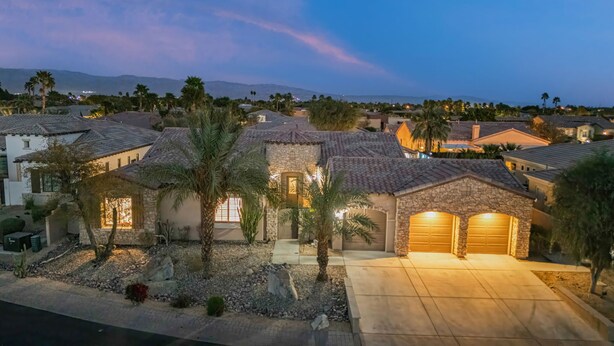 A residential area with houses featuring stone and tiled roofs, palm trees, and a clear view of distant mountains. - ALL INCLUSIVE - SUPER MARIO RETREAT – EPIC GAMING GETAWAY (Indio)