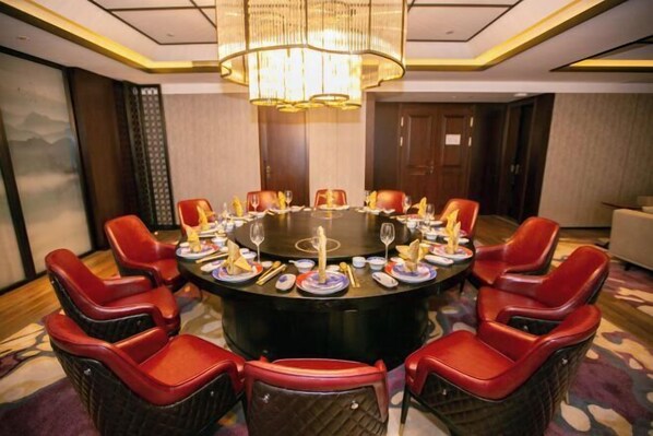 A conference room with a round table, red chairs, and a chandelier. - TAIZHOU RIVERVIEW INTERNATIONAL HOTE (Linhai)