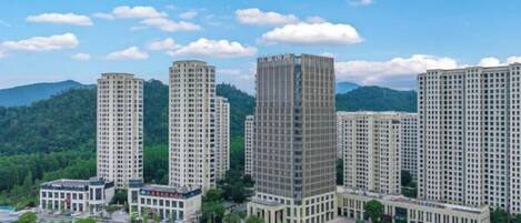A high-rise residential building complex with multiple apartment buildings, surrounded by greenery and a clear sky.