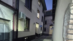 A narrow alleyway with a checkered pavement, buildings with windows and doors, and a visible air conditioning unit. - Vazira Hotel (Samarkand)