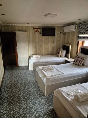 A hotel room with two beds, a television, and an air conditioning unit. - Vazira Hotel (Samarkand)