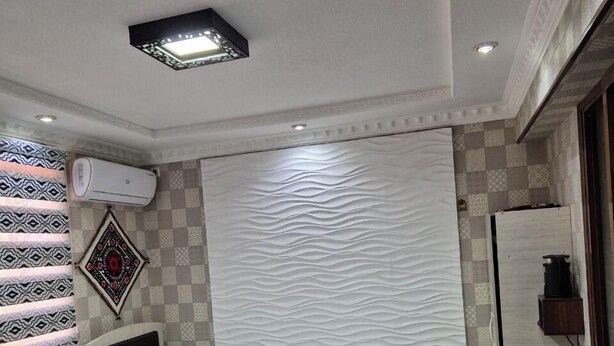 A neatly arranged bedroom with a bed, bedside tables, an air conditioning unit, and a patterned wall. - Vazira Hotel (Samarkand)