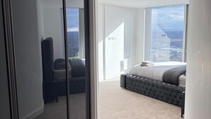 A modern bedroom with a large bed, a seating area, and a city view. - 3Bed Apt Sleeps 6 - City Central with Wifi (Manchester)