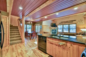 A wooden interior with a kitchen, dining area, and staircase.