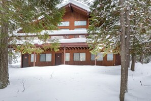 A wooden cabin with a balcony, surrounded by snow-covered trees. - New! Lake Access, Pools/Hot Tub & Ski Area Proximity (Whitefish)