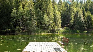 A wooden dock extending into a pond surrounded by dense forest. - New! Lake Access, Pools/Hot Tub & Ski Area Proximity (Whitefish)