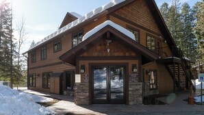A lodge with a wooden exterior, large glass doors, and a staircase leading to an upper level. - New! Lake Access, Pools/Hot Tub & Ski Area Proximity (Whitefish)
