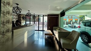 A modern reception area with a reception desk, seating, and a large window offering a view of the street. - Le Bus  (Pattaya)