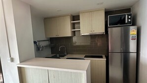 A modern kitchen with a stainless steel refrigerator, a microwave, and a sink. - Le Bus  (Pattaya)