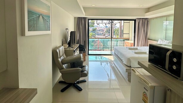 A modern hotel room with a dining area, a sofa, a desk, and a refrigerator. - Le Bus  (Pattaya)
