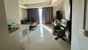A modern living room with a sofa, a coffee table, a TV, and a leather chair. - Le Bus  (Pattaya)