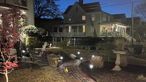 A brick pathway leading to a house with a porch and a covered front porch area.
