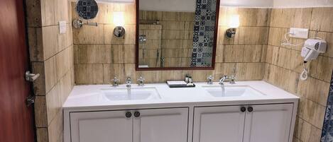 A bathroom with a double sink vanity, a mirror, and a towel rack.