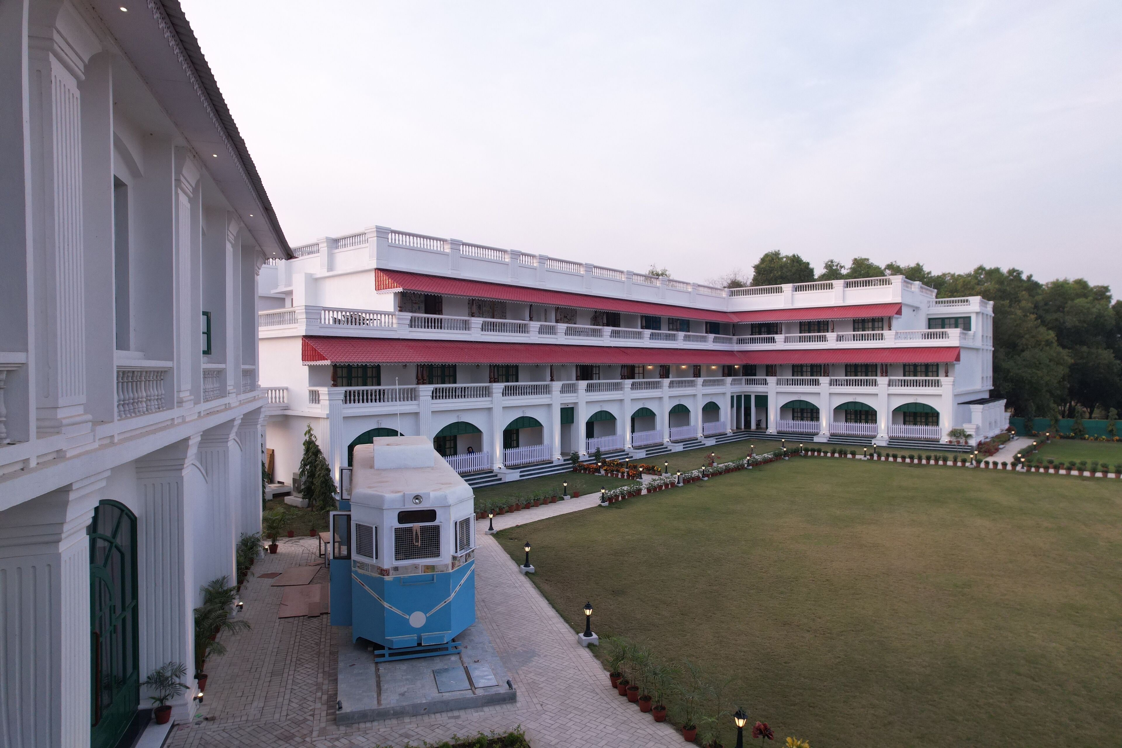 A large, multi-story building with a central courtyard, featuring a blue and white structure in the foreground.